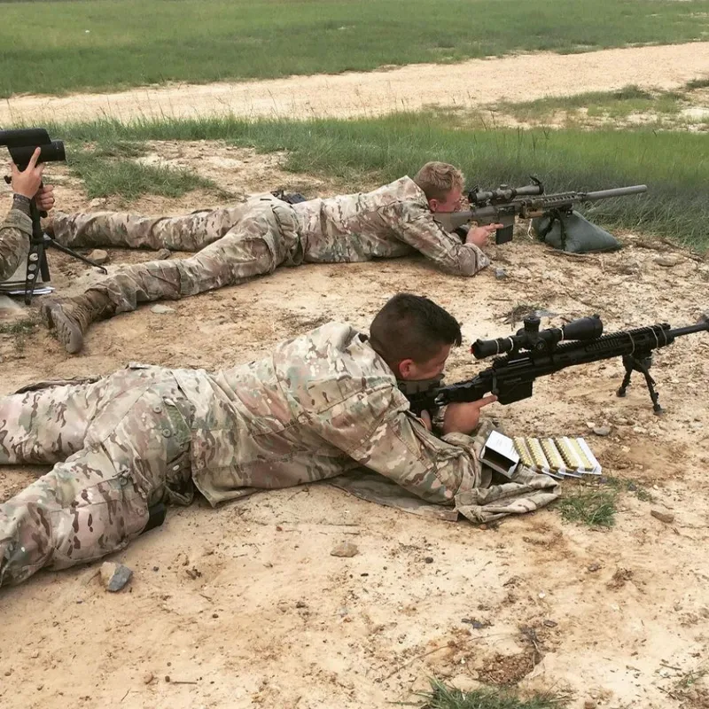 Two military people sleeping in position with guns